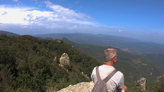 坐在西班牙河山顶的岩石上欣赏西班牙壮丽的山峰视频的预览图