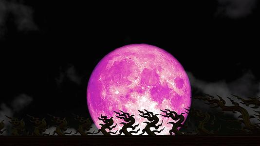 在夜空和模糊的乌云中超级粉色的草莓月亮在屋顶上闪耀视频的预览图