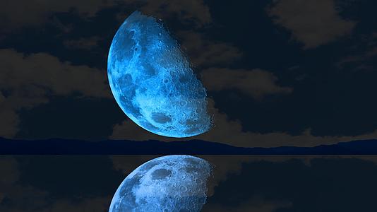 半个蓝色的月亮在黑暗的天空中升起在湖面上方视频的预览图