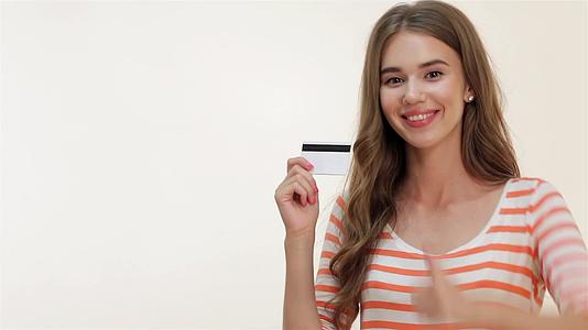 吸引人的女孩用信用卡显示高拇指视频的预览图