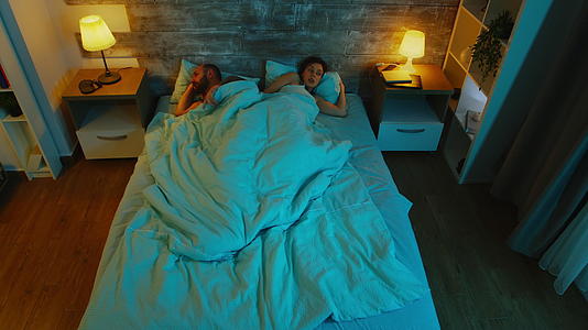 在床单下年轻夫妇的顶部风景在分歧后无法入睡蓝色的月光视频的预览图