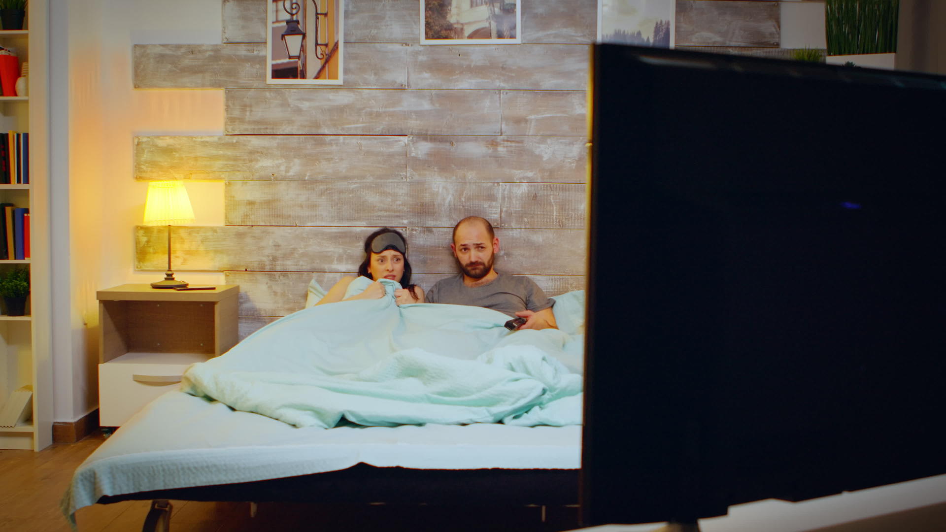 卧室里的男朋友和女朋友穿着睡衣看恐怖电影视频的预览图