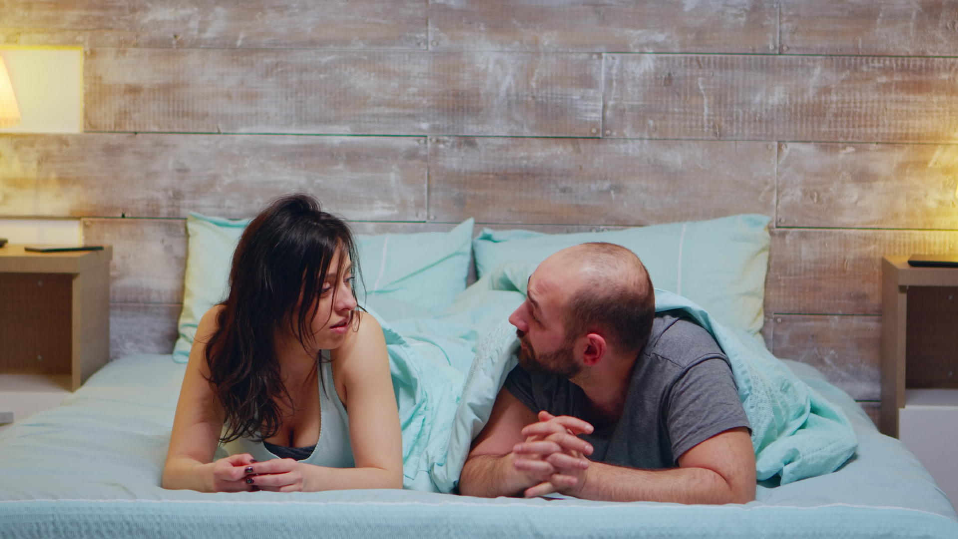 躺在床上穿着睡衣的年轻夫妇谈视频的预览图