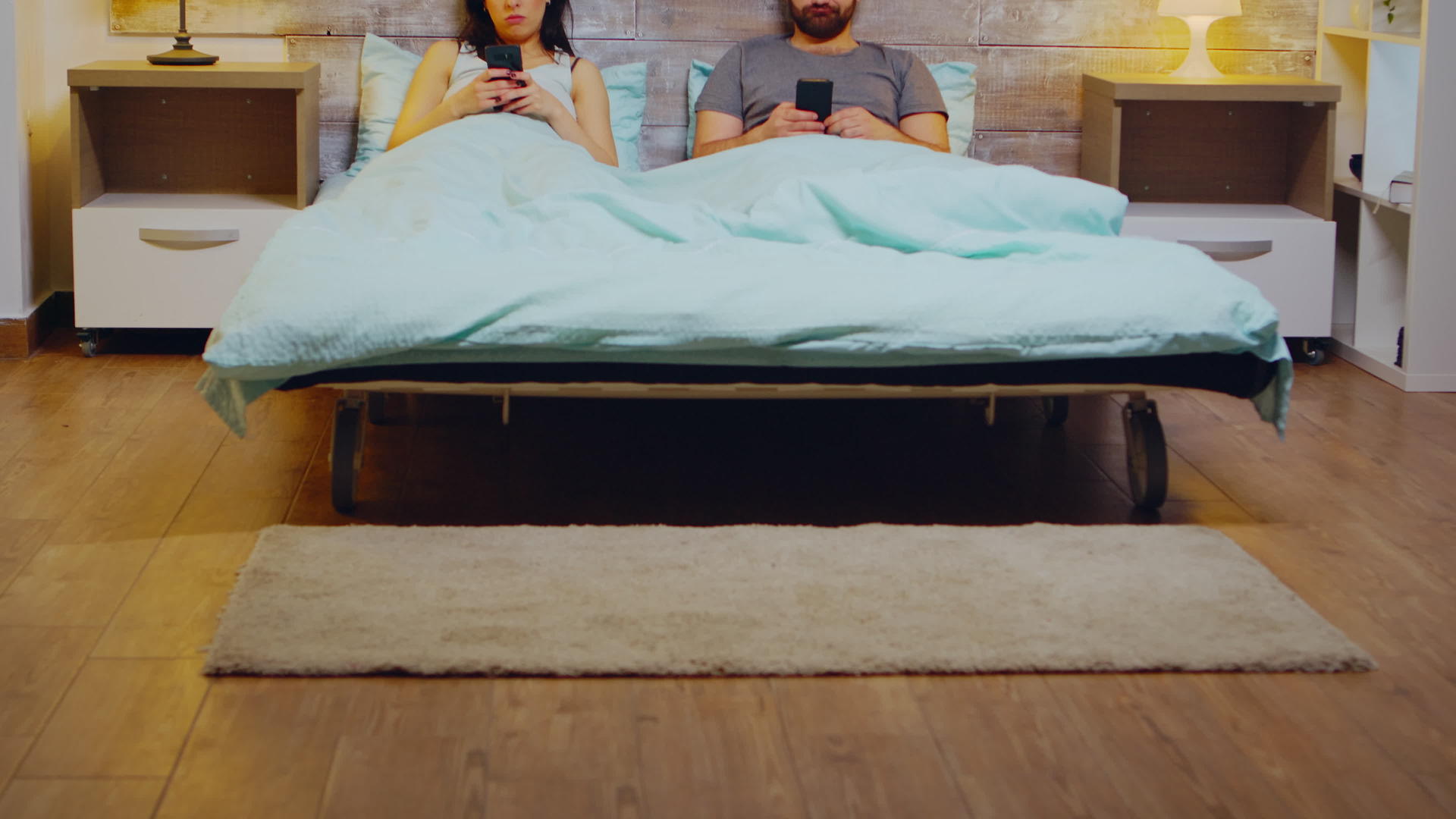 一对无聊的年轻夫妇晚上穿着睡衣睡在床上用智能手机睡觉视频的预览图