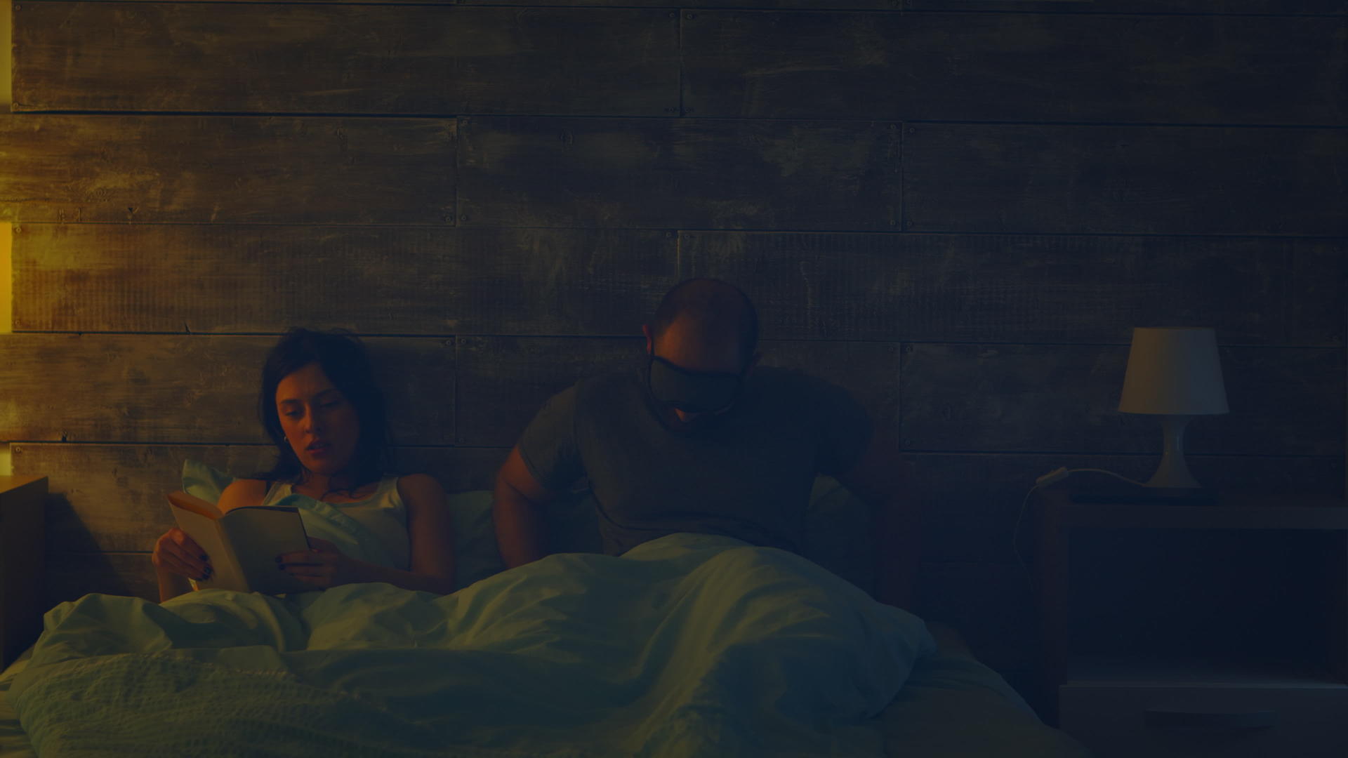 当丈夫想睡觉时女人在夜灯前在床上看书视频的预览图