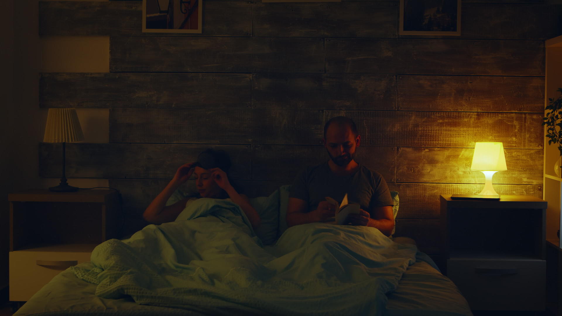 一个年轻人正在读一本书他的妻子正在关灯睡觉视频的预览图