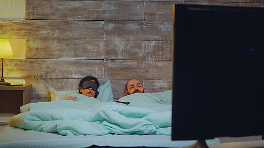 睡在卧室里的年轻夫妇在电视机前睡着了视频的预览图