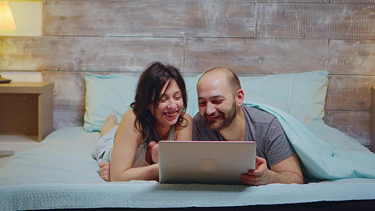 使用笔记本电脑的情侣们穿着睡衣微笑视频的预览图
