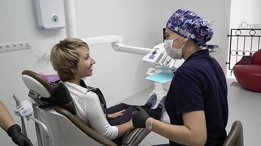 牙医和患者在咨询医疗设备时选择治疗视频的预览图