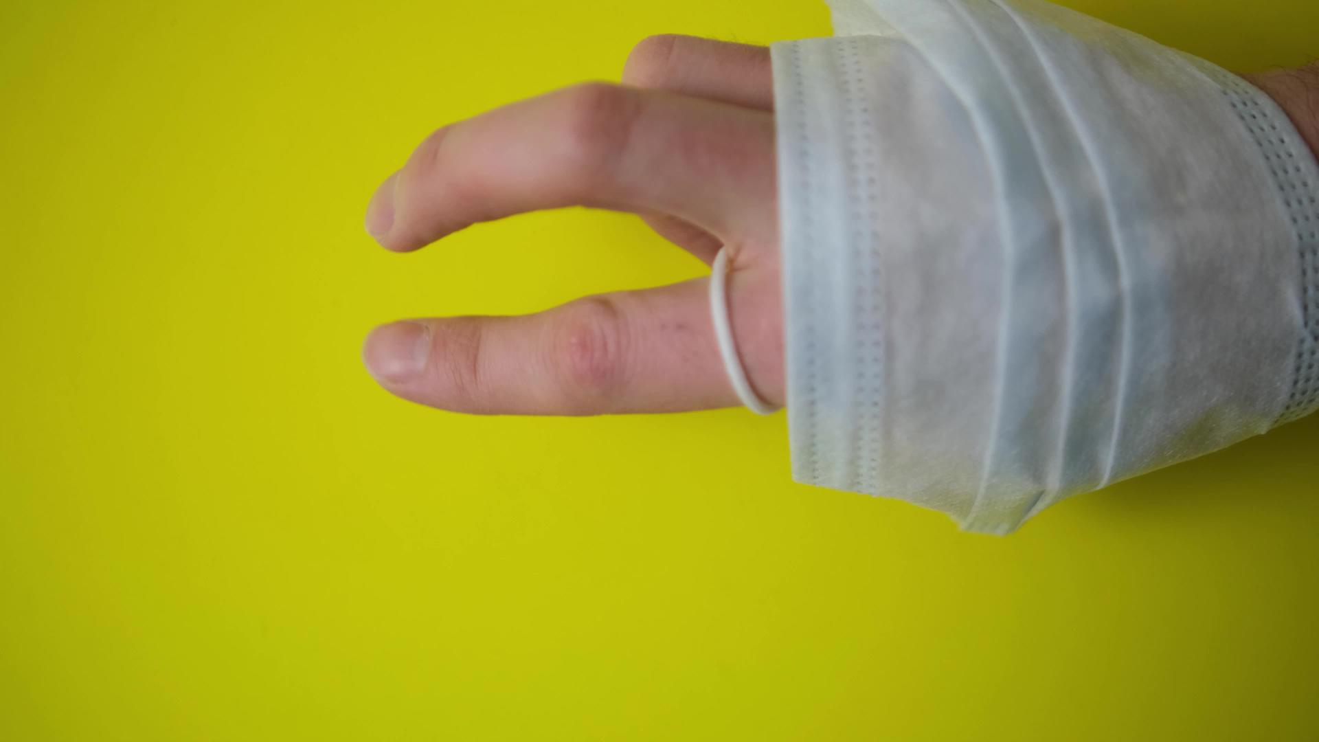 保护性医用口罩缠绕在手臂上背景为黄色涂有艺术涂层视频的预览图