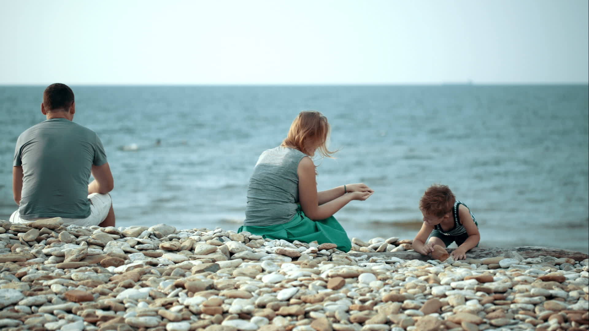 父母和小儿子在石头沙滩上视频的预览图