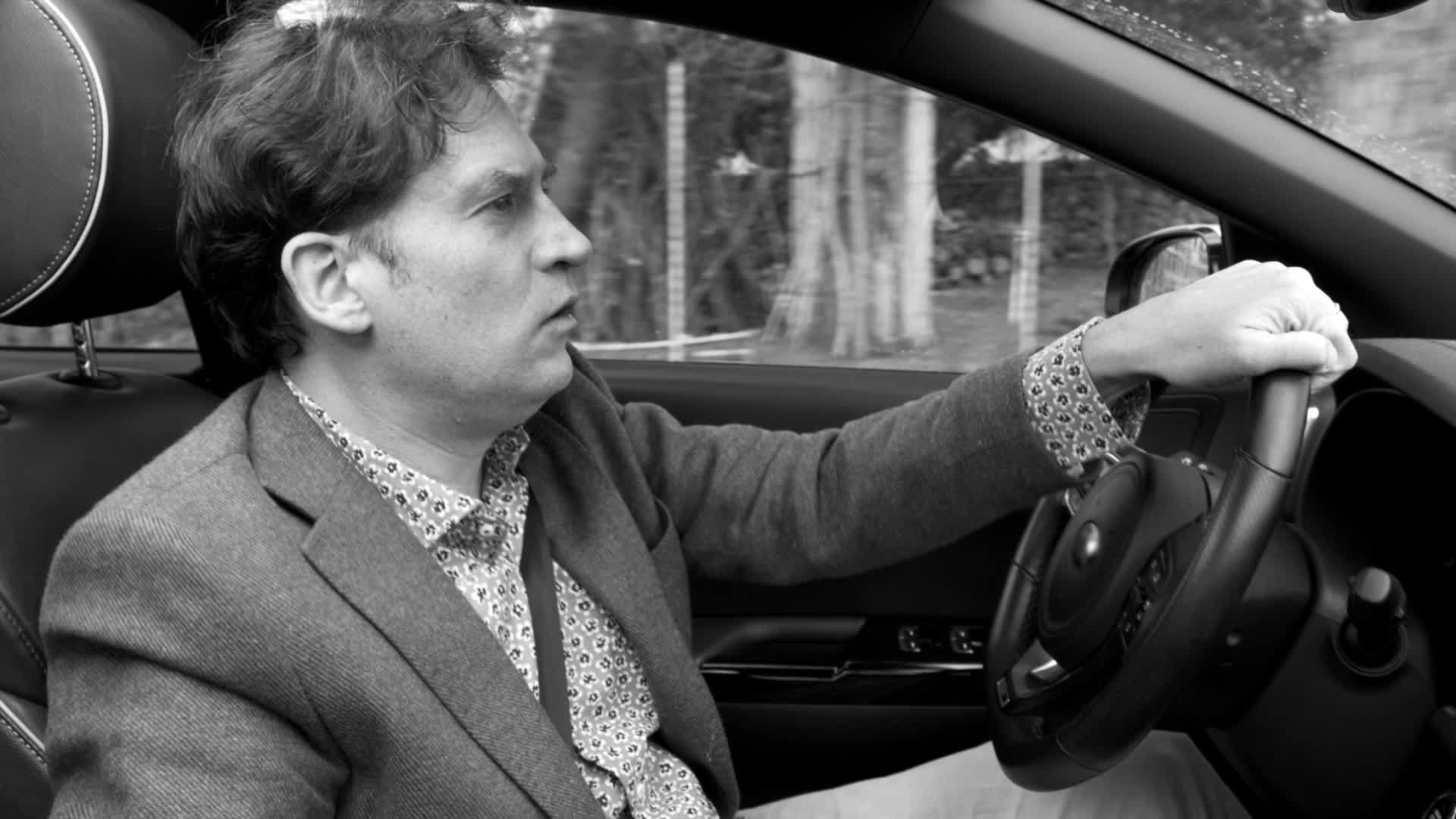 一名男子严肃地驾驶汽车唱着慢歌黑白运动视频的预览图