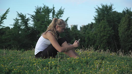 坐在山上的年轻女孩衬衫在你的手机上获取信息视频的预览图