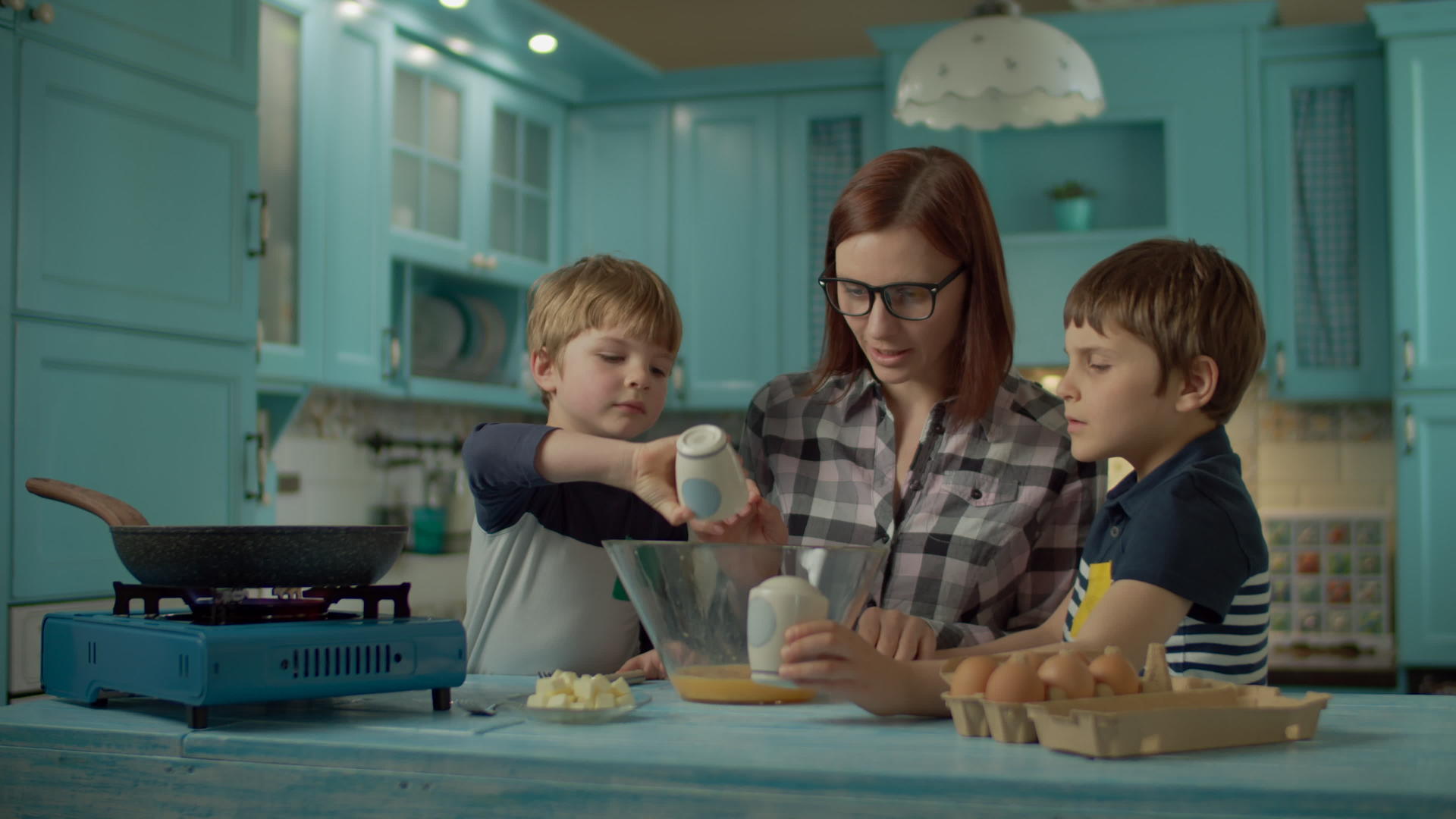 在家里的蓝色厨房里母亲和两个儿子一起煮炒蛋视频的预览图