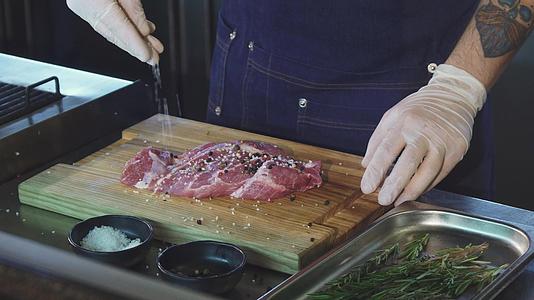一位厨师在煮牛排前给猪肉加盐视频的预览图
