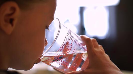 小女孩用一个大玻璃杯喝水视频的预览图