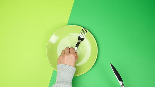绿色表面的两只手一把圆形陶瓷板叉和一把刀视频的预览图