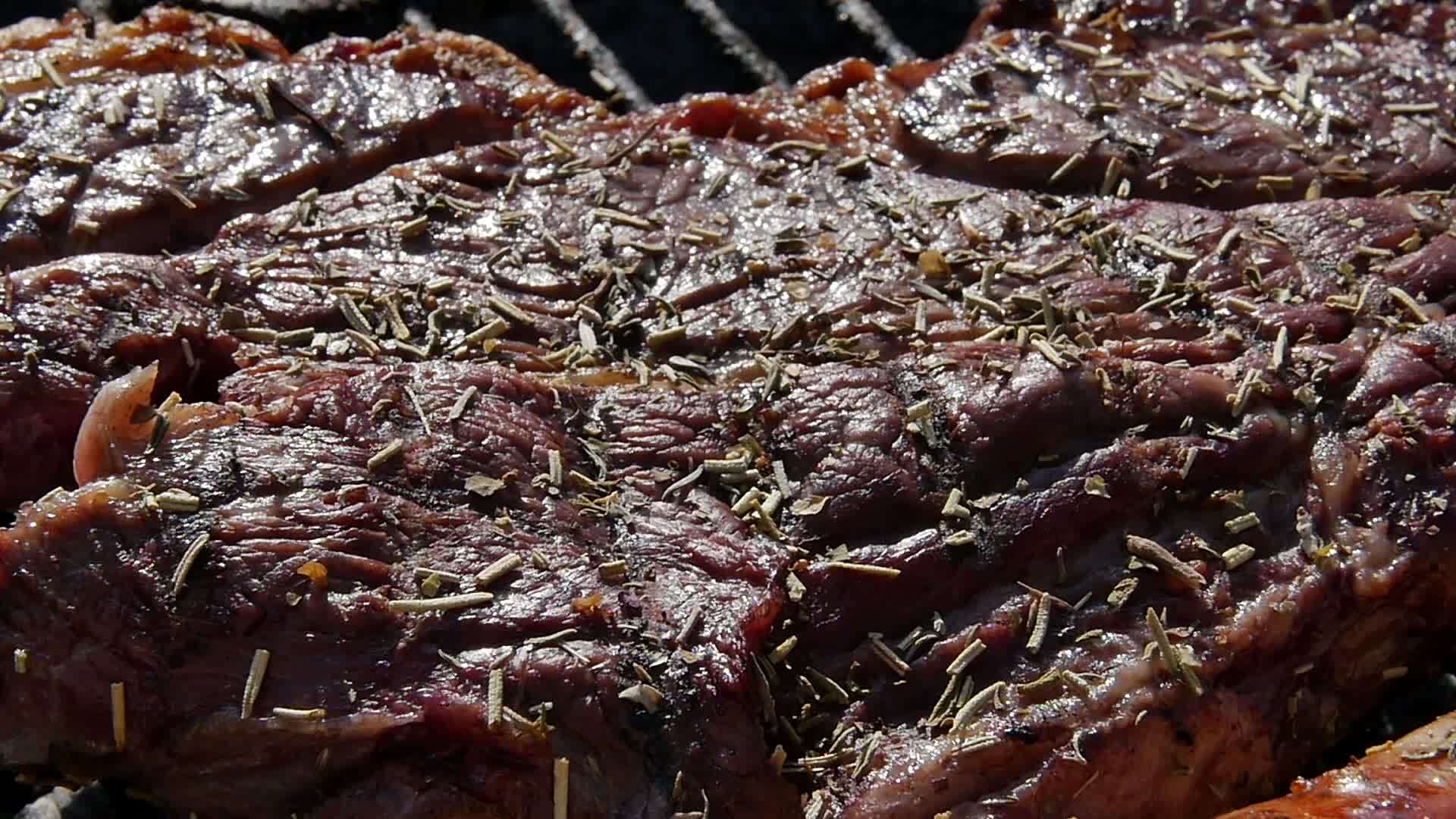 烧烤架上生牛排在燃烧的热煤上嘶嘶作响的特写视图视频的预览图