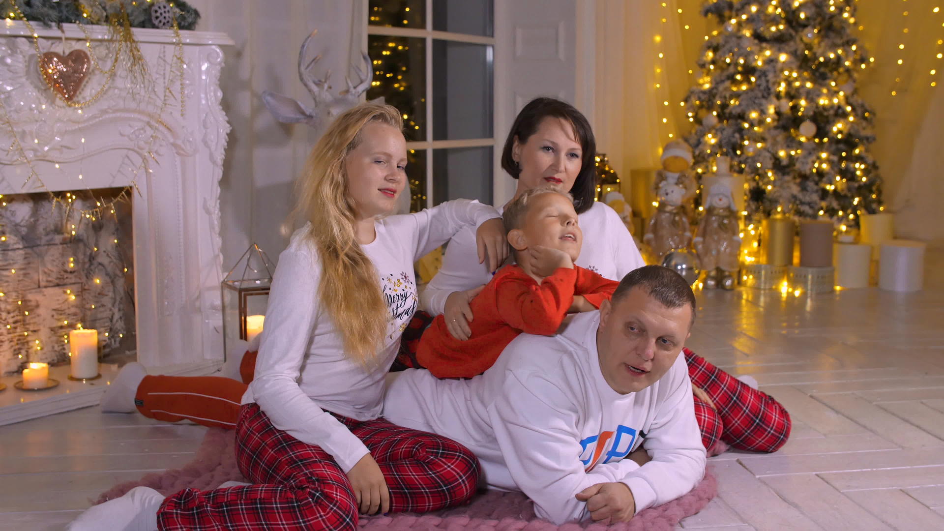 地毯上的家庭在圣诞树和家庭壁炉的背景下视频的预览图