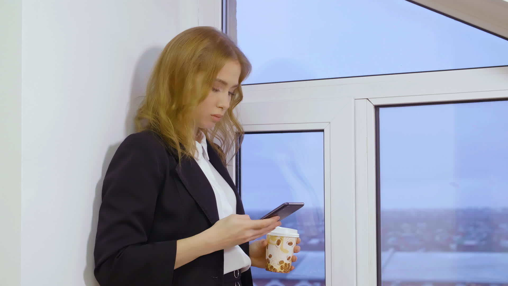 公司女经理在智能手机上发短信在窗口附近端咖啡杯视频的预览图