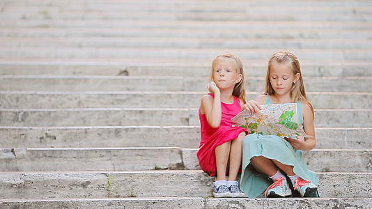 可爱的小女孩在意大利的阶梯上看着旅游地图快乐的孩子们视频的预览图