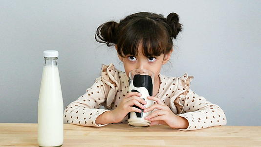 可爱的女孩喝新鲜牛奶的肖像视频的预览图