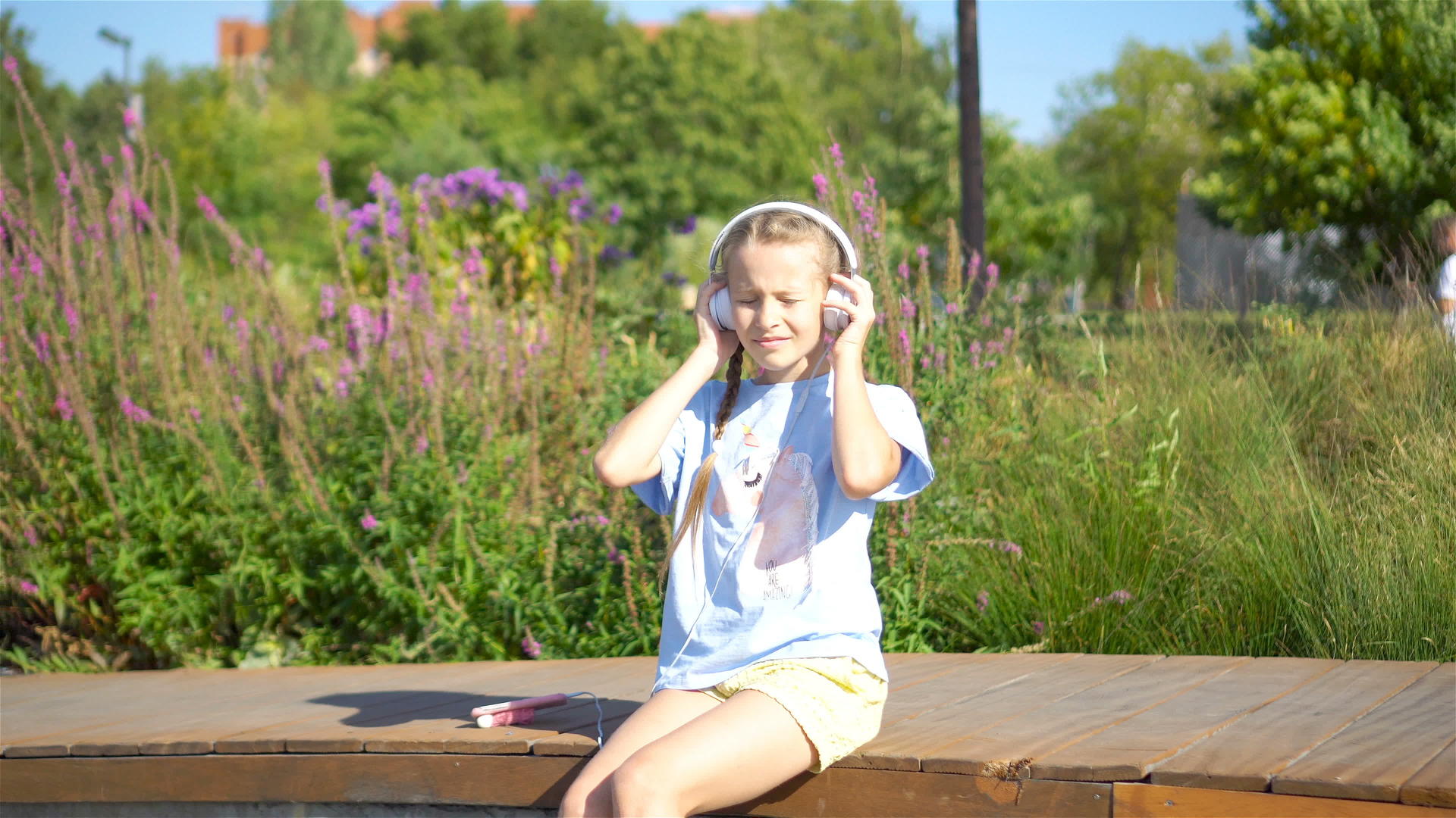 小女孩在公园里听音乐的声音视频的预览图