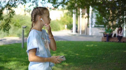 小女孩在公园里听音乐的声音视频的预览图