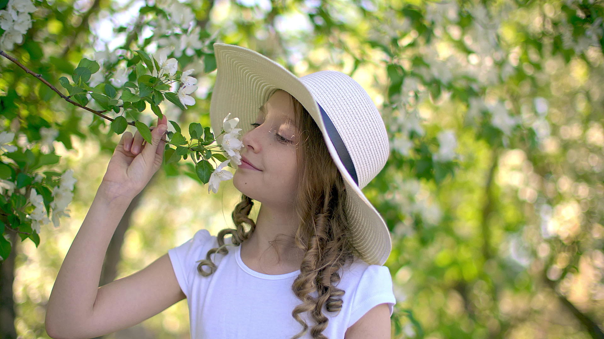 春天的一天可爱的女孩在果园里嗅着花枝微笑着视频的预览图