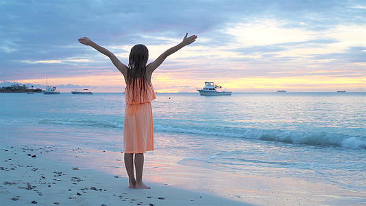 日落时走在白色沙滩上的小女孩视频的预览图