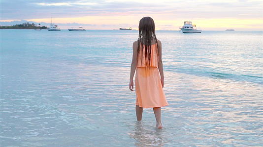 可爱快乐的小女孩日落时在白色沙滩上散步的慢动作视频视频的预览图