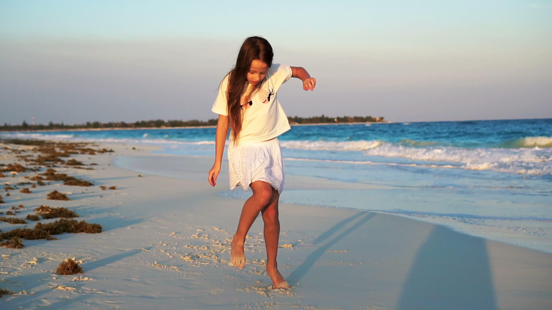 小女孩在白色的海滩上日落视频的预览图