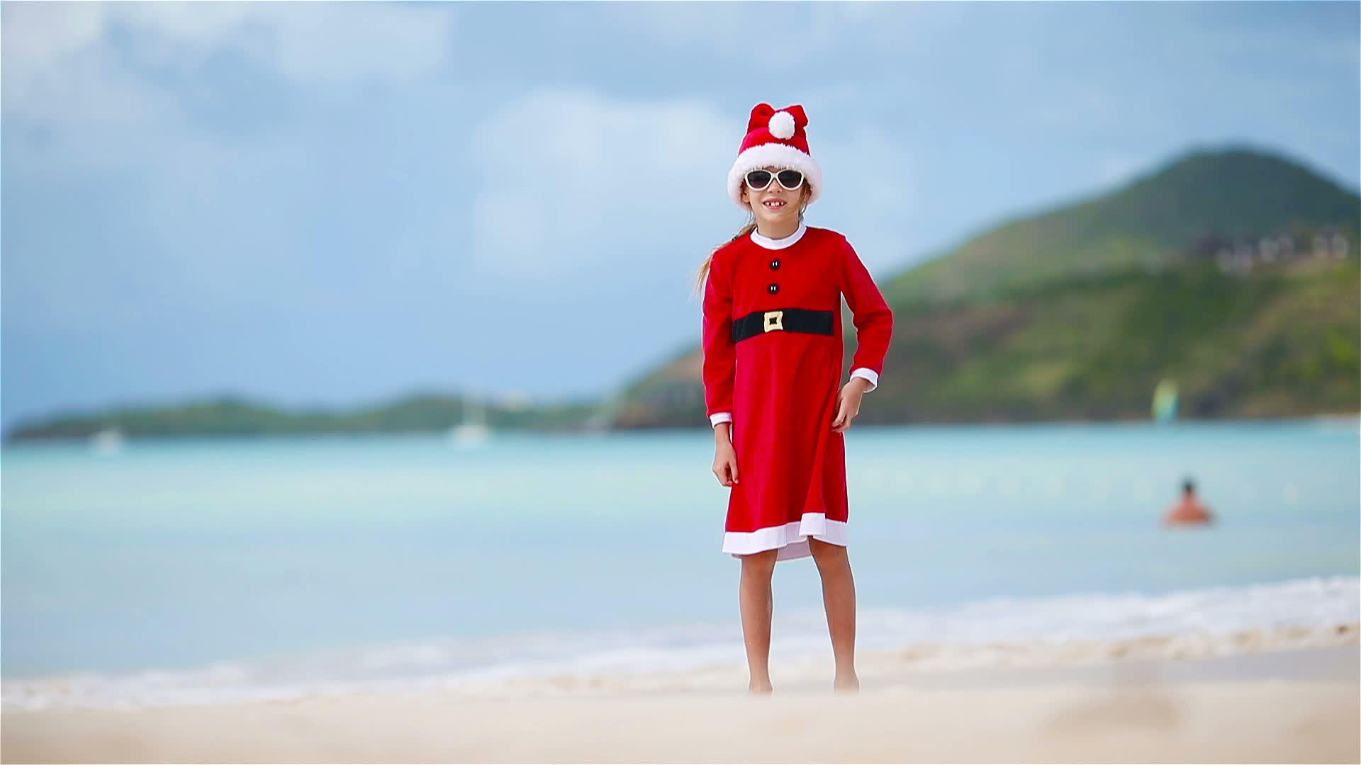 圣诞节期间女孩在白色海滩上戴着圣诞帽视频的预览图
