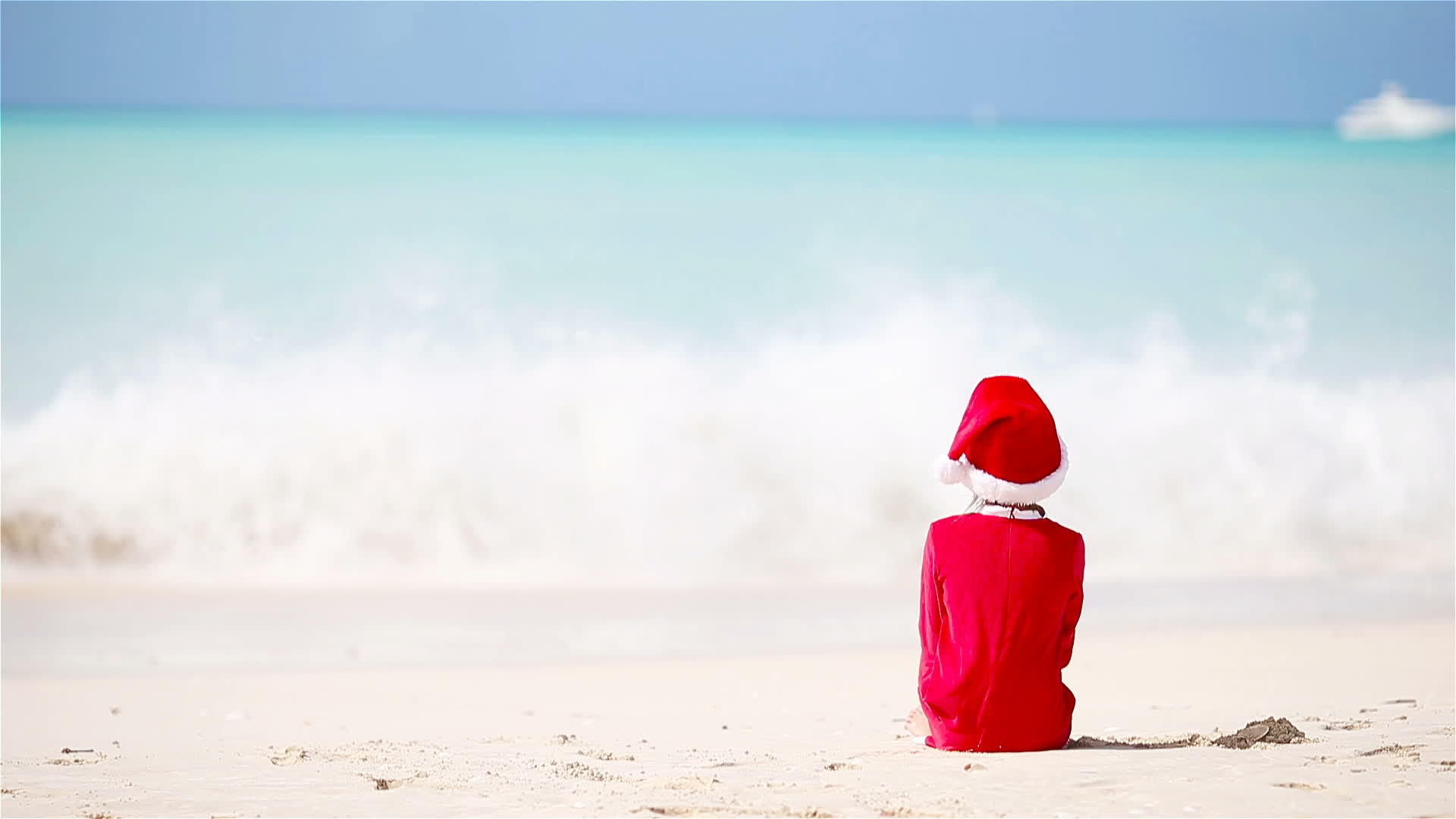圣诞节期间可爱的女孩在白色海滩上戴着圣诞帽子视频的预览图