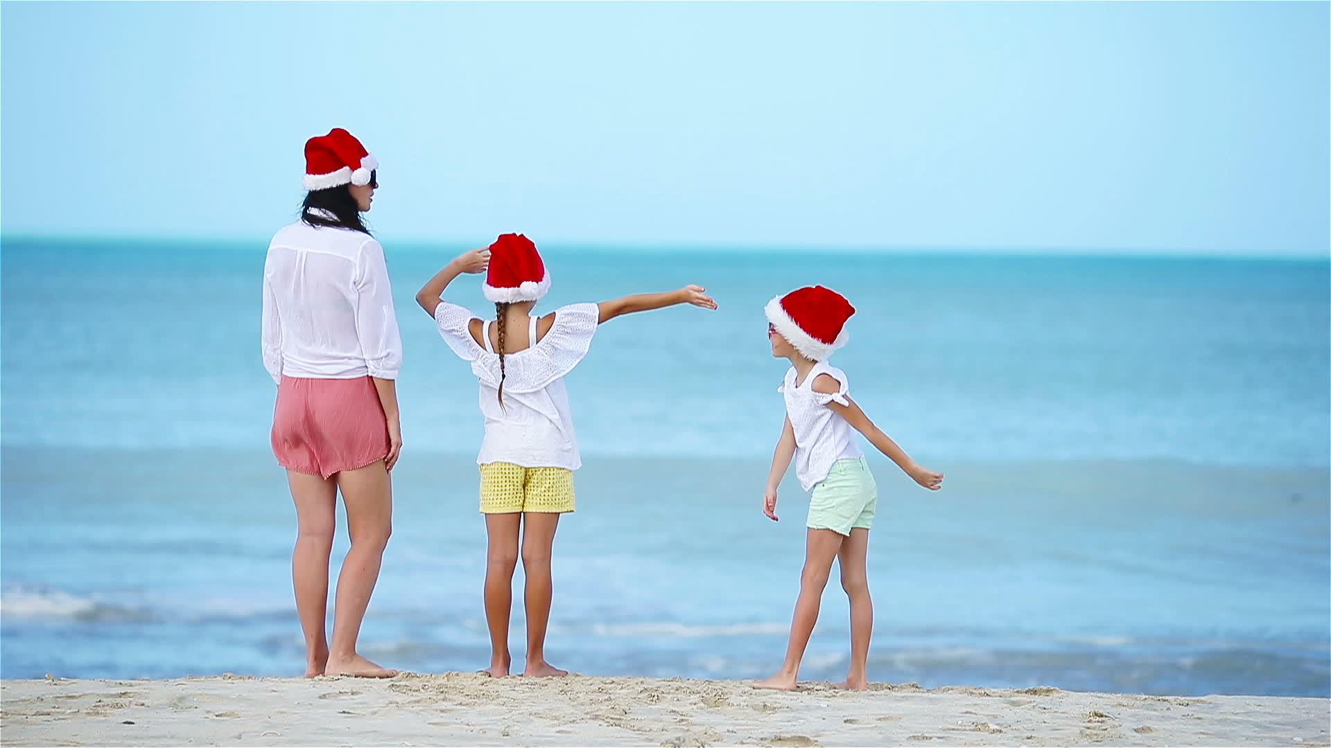 圣诞节期间白色海滩上的家庭戴着圣诞帽子视频的预览图