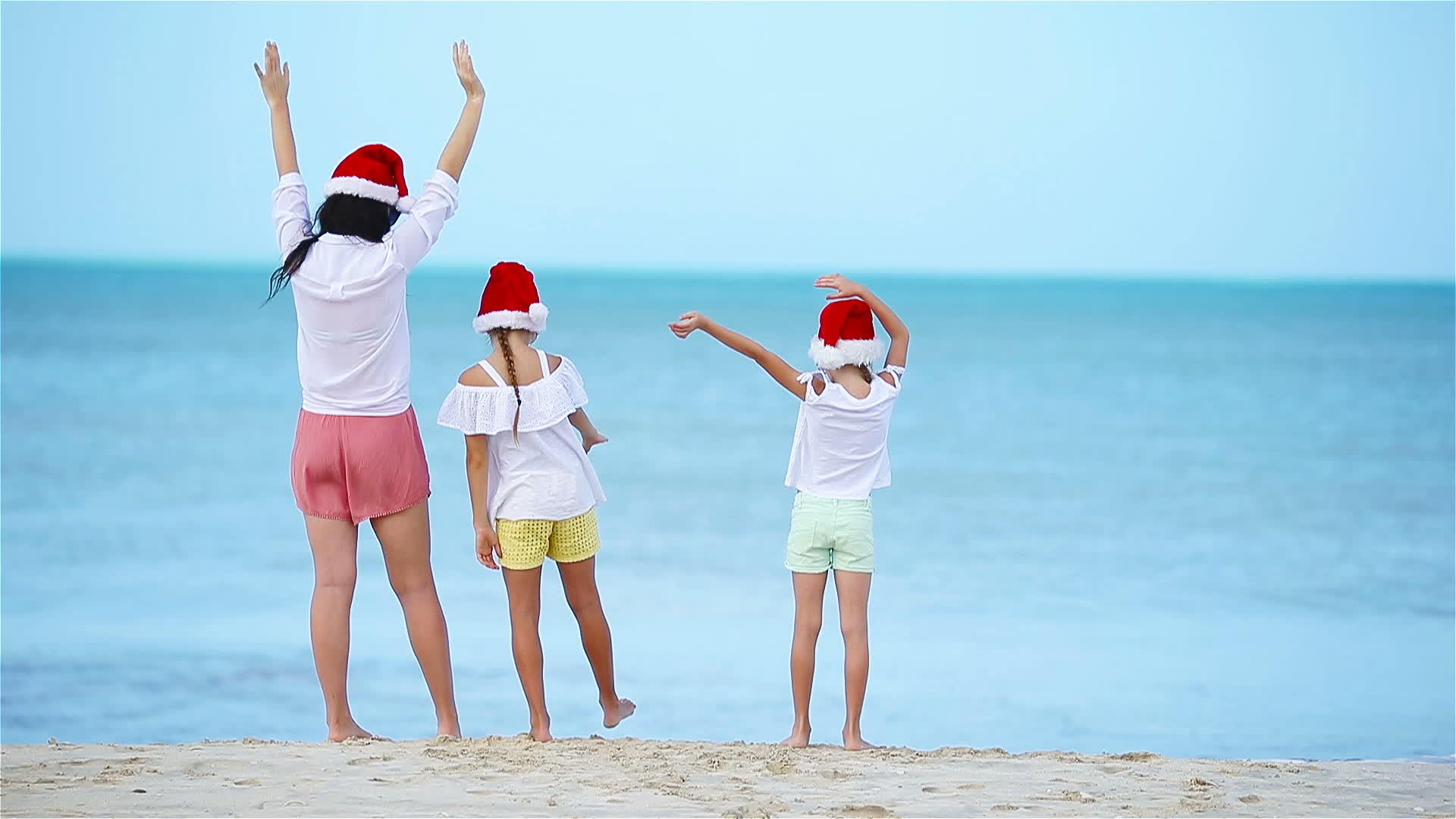 圣诞节期间一个可爱的女孩在白色海滩上戴着圣诞帽子视频的预览图