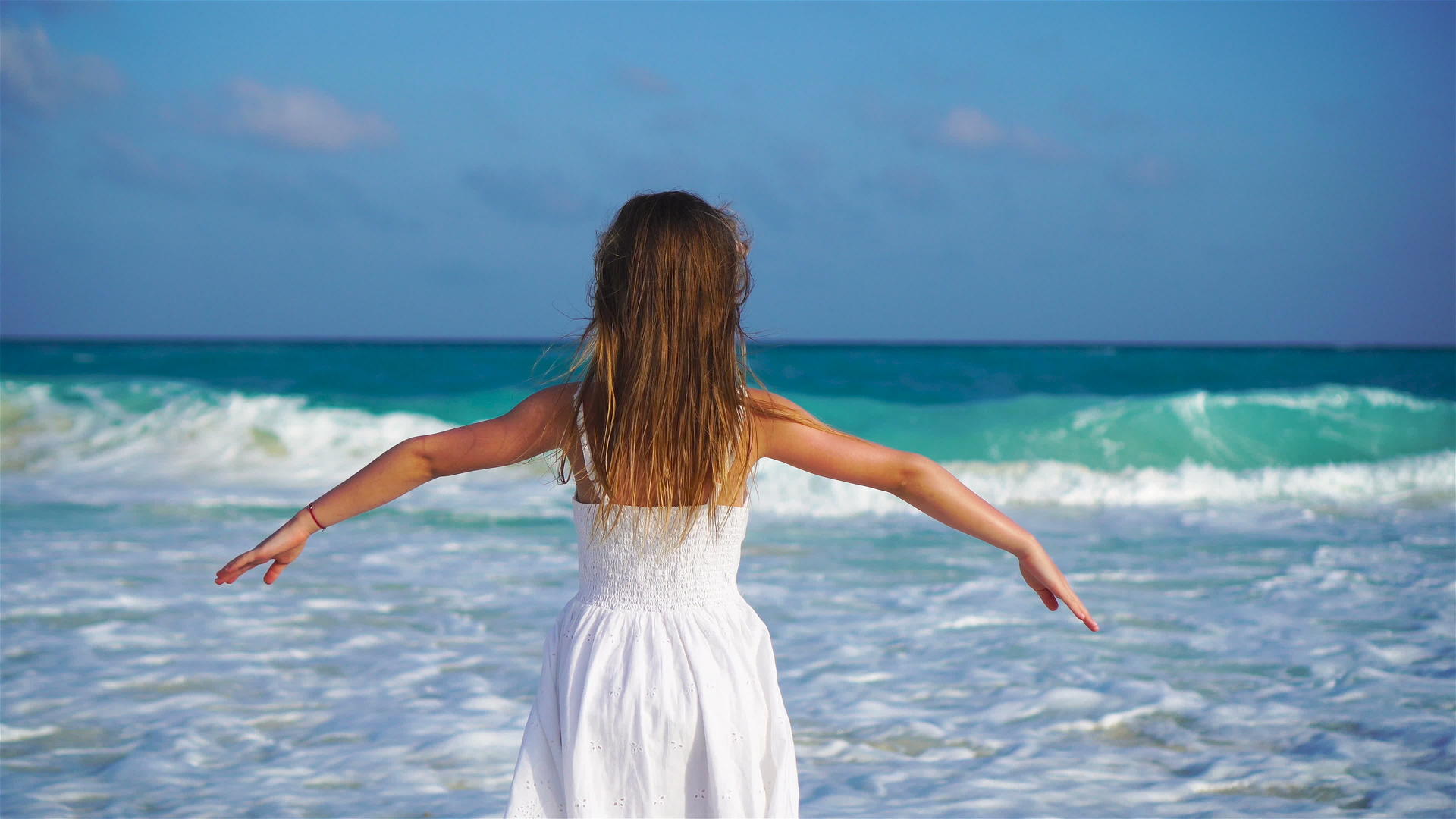 可爱快乐的小女孩看着白色海滩上嘈杂的大海和大海视频的预览图