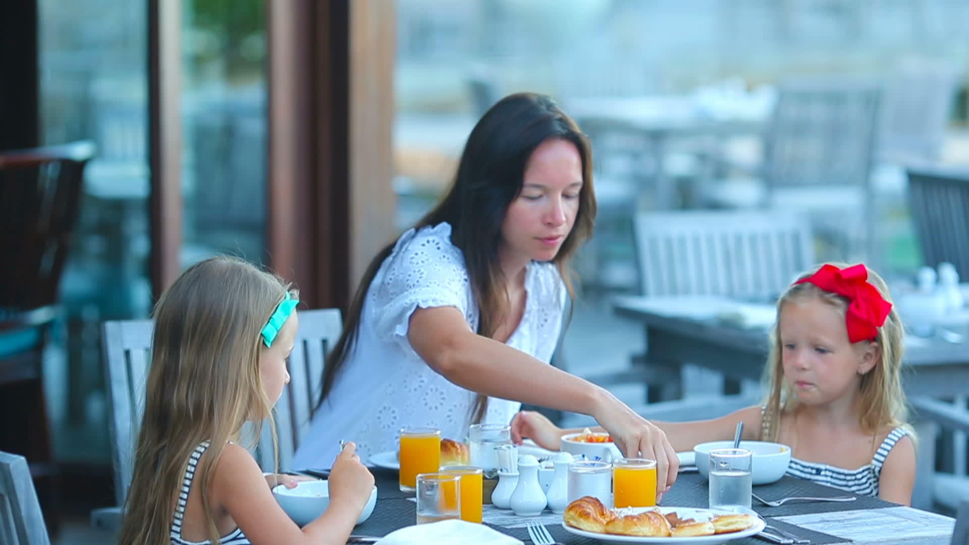 年轻的母亲和可爱的小女孩在户外咖啡馆吃早餐视频的预览图
