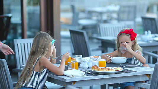 可爱的小女孩在户外咖啡馆吃早餐视频的预览图