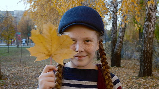 快乐的女孩在公园里拿着树叶视频的预览图