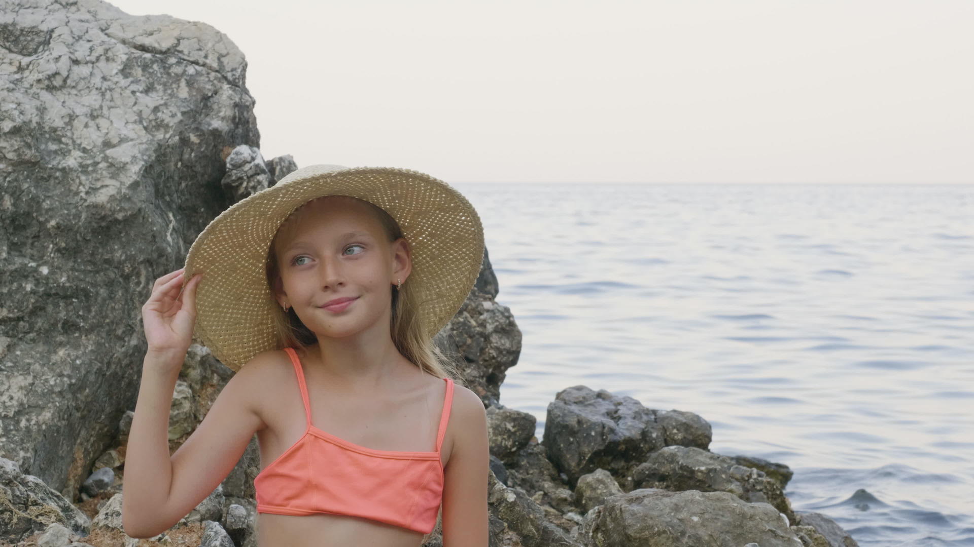 戴着帽子的美丽女孩微笑着在海景中摆姿势视频的预览图