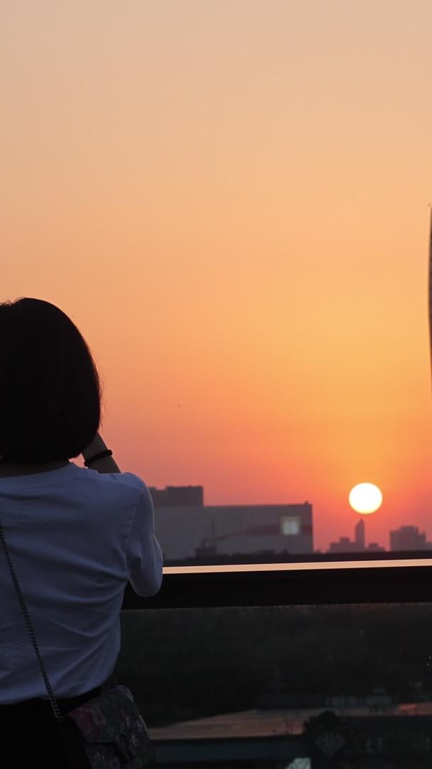 用手机拍摄夕阳美景的女孩背影视频的预览图