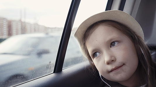 小女孩在阳光明媚的日子从窗户往外看的小女孩视频的预览图