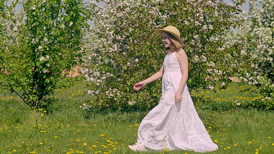 小女孩带着美丽的树木走在花园里视频的预览图