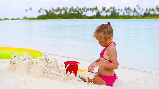 小女孩在热带度假期间玩沙滩玩具视频的预览图