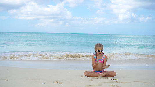可爱的小女孩躺在白色的海滩上视频的预览图