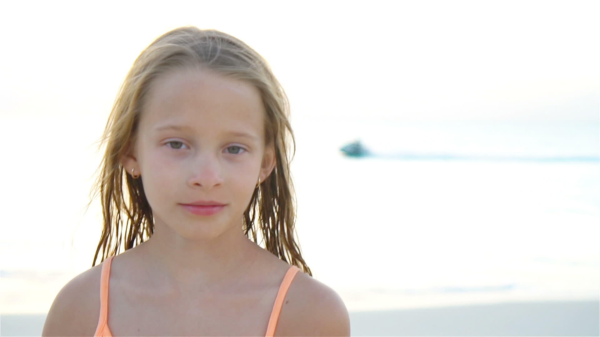 小女孩的肖像看着镜头和微笑的背景天和海的照片视频的预览图
