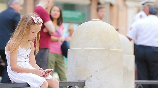 可爱的小可爱女孩拥有智能手机在欧洲城市的户外fontana视频的预览图