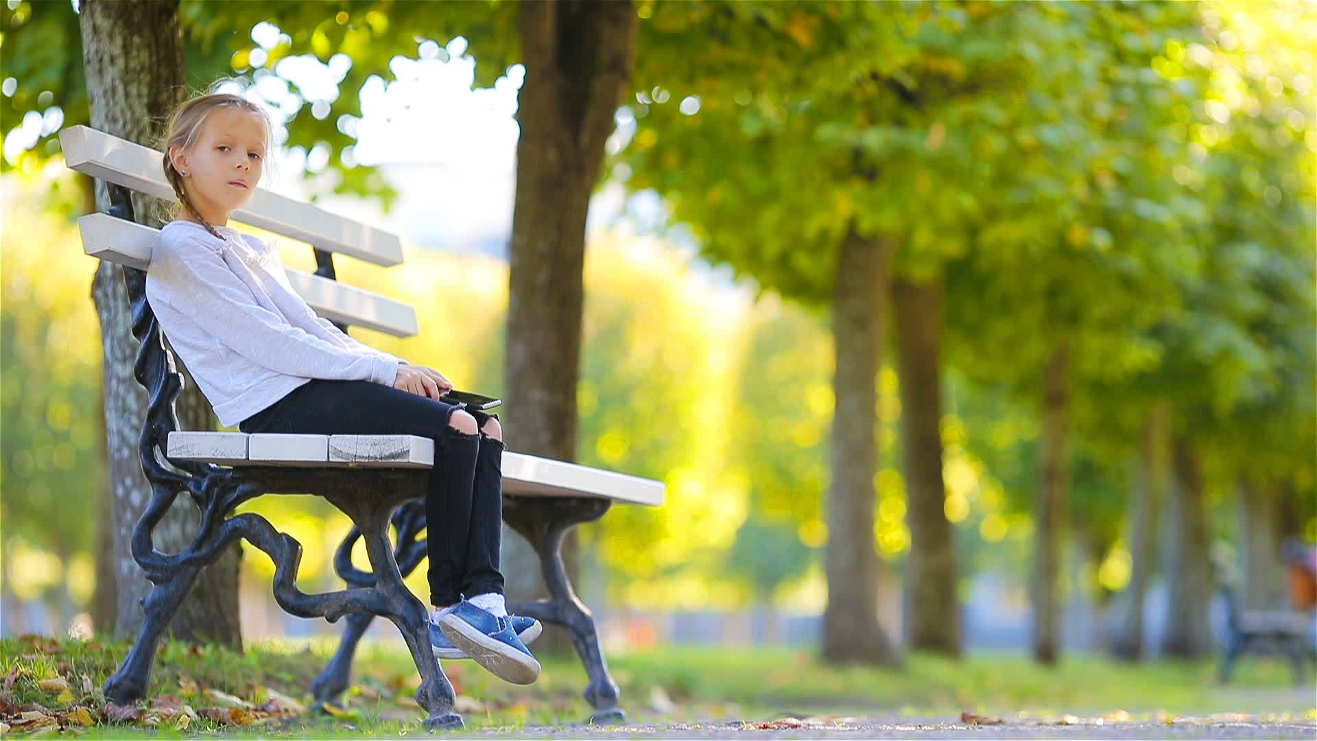 秋天的女孩坐在公园的凳子上视频的预览图