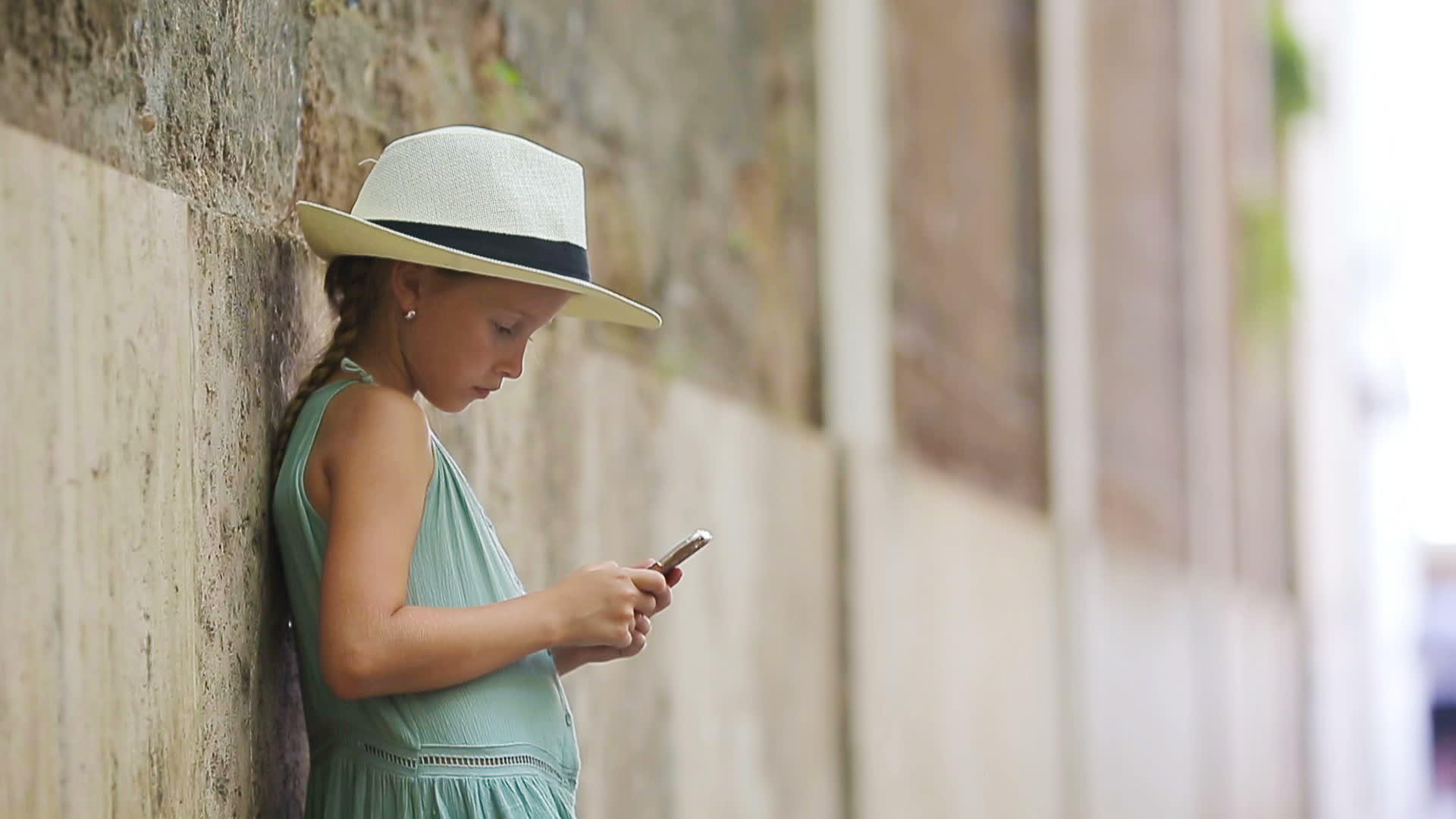 可爱的小女孩在温暖的欧洲城市的户外日间使用手机视频的预览图